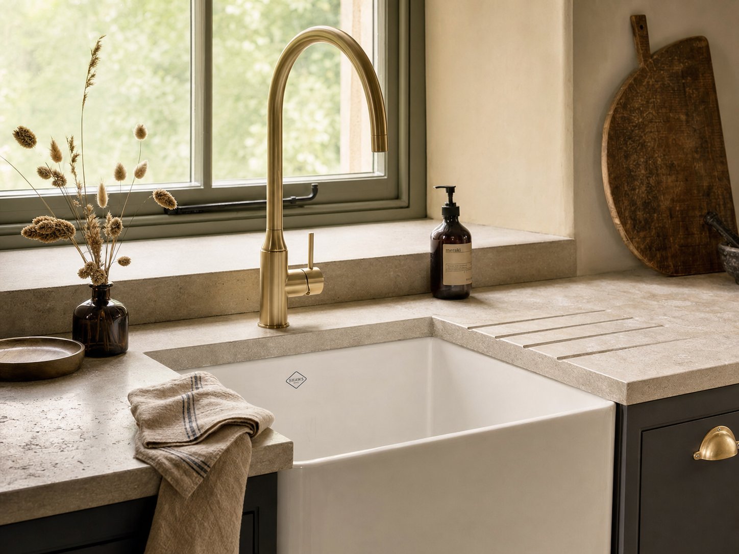 Newly installed brushed-brass luxury kitchen tap over a farmhouse sink